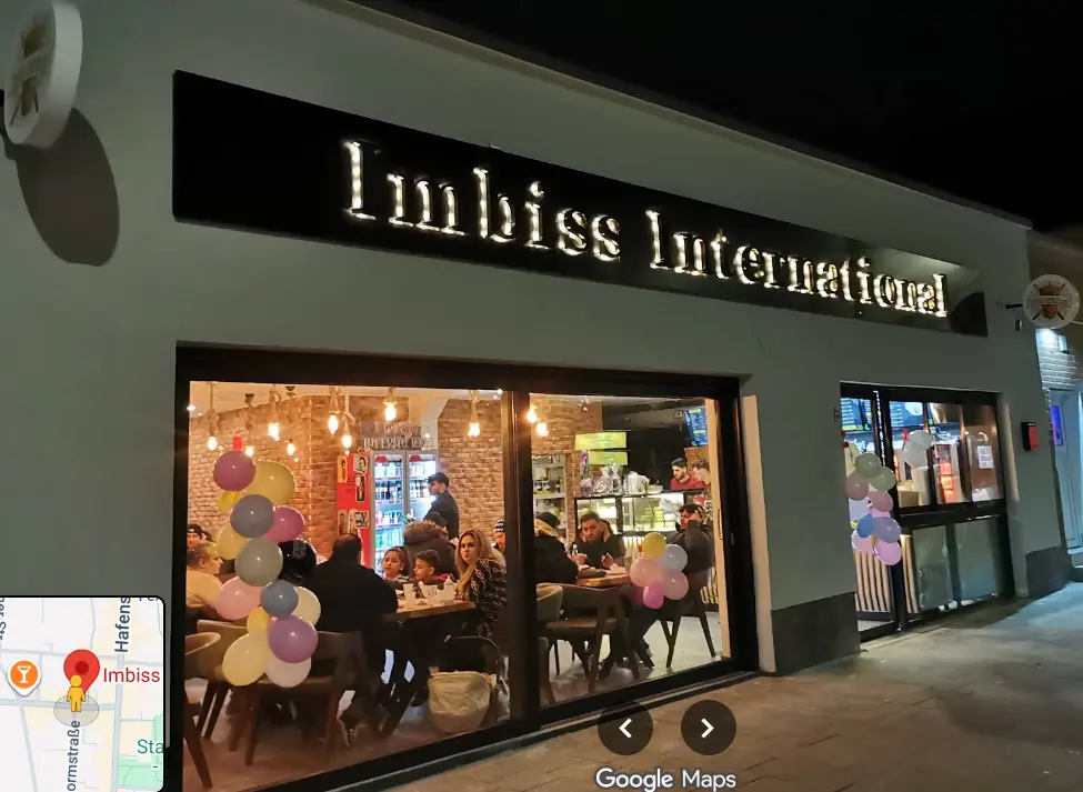 Beleuchtete Außenansicht von Imbiss International am Abend