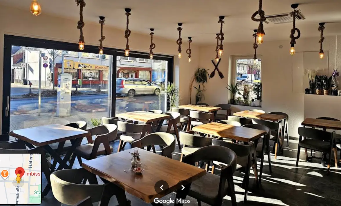 Heller modernisierter Gastraum mit Holztischen und dunklen Stühlen bei Imbiss International